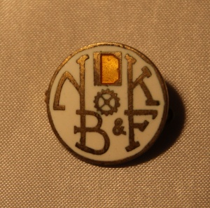 Norsk Bokbinder- og Kartonasjearbeiderforbund nål - stiftet i 1898 gikk inn i Norsk Grafisk Forbund i 1966 (gullskrift med hvit bakgrunn)