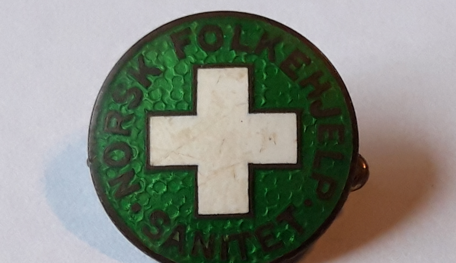 Norsk Folkehjelp Sanitet nål fra 1939 - logoen er den første som ble benyttet. Merke tilhører  John Magnor Olsen